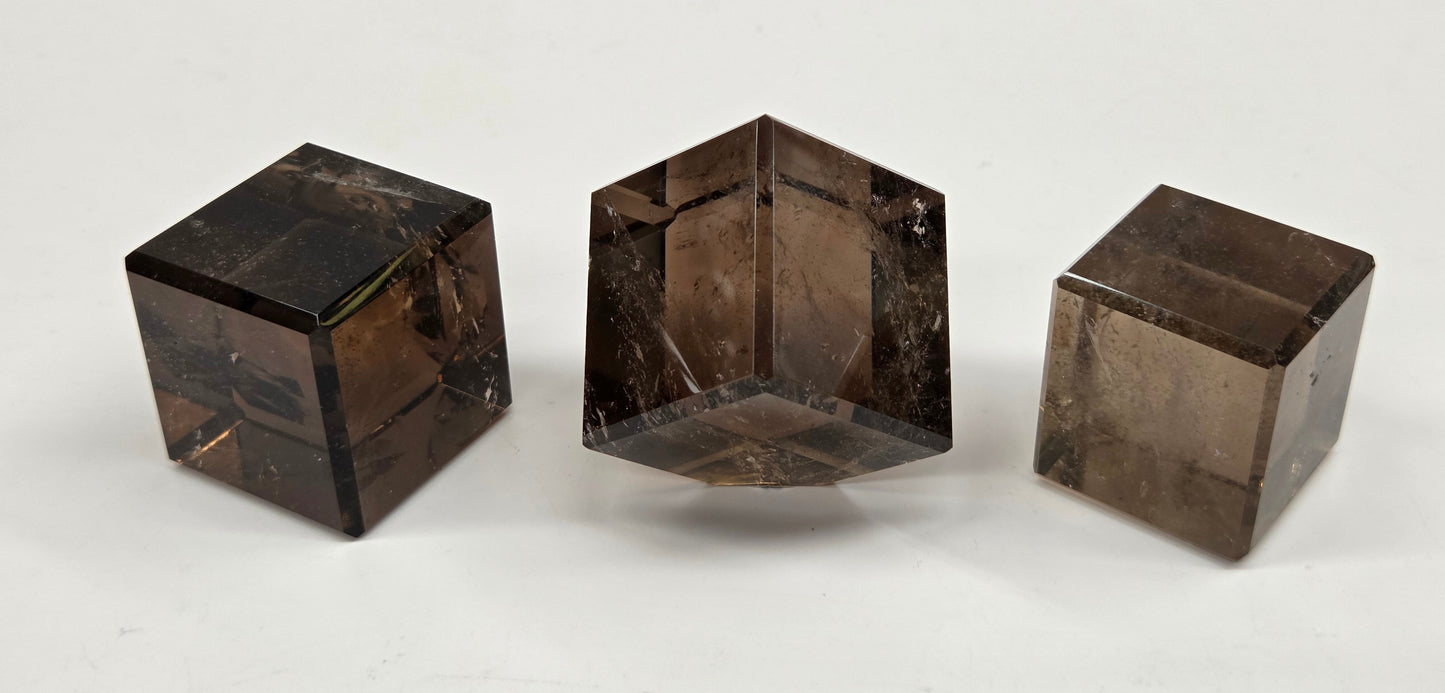 Three smoky quartz cube carvings on a white background