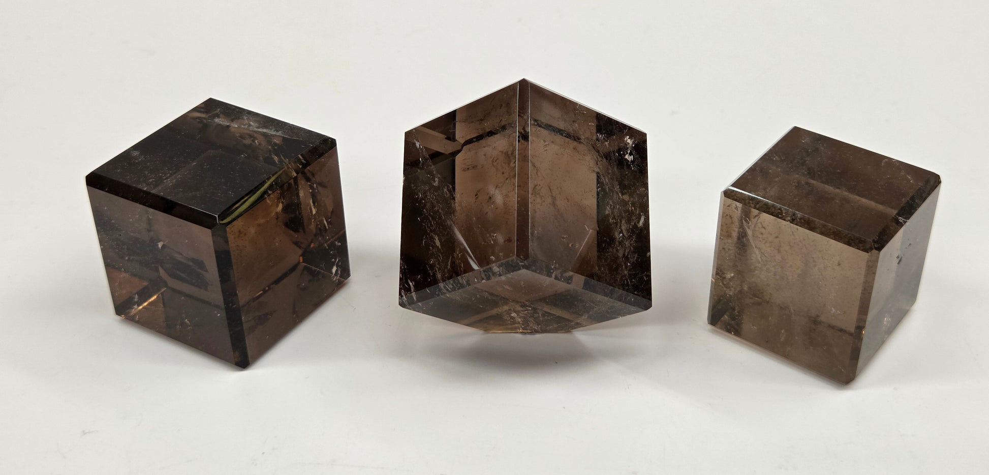 Three smoky quartz cube carvings on a white background