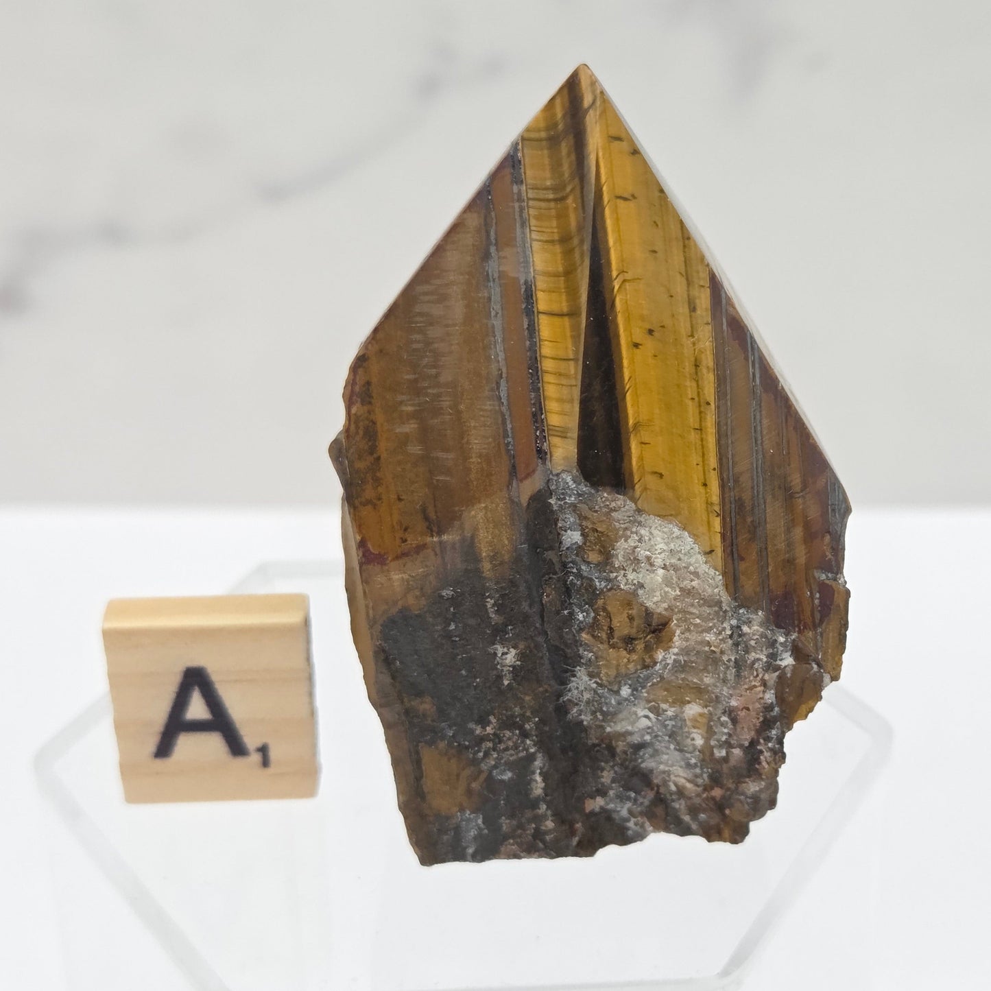 Tigers Eye specimen on a white background with a small wooden block displaying 'A' 