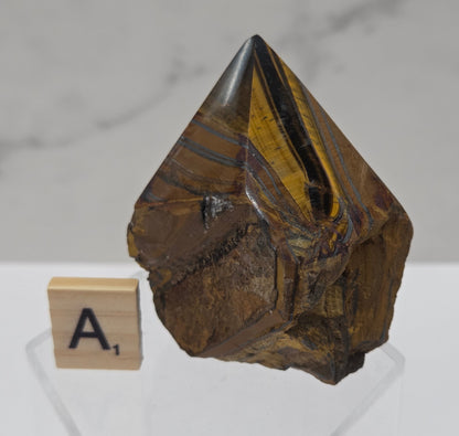 Tigers Eye specimen on a white background with a small wooden block displaying 'A' 