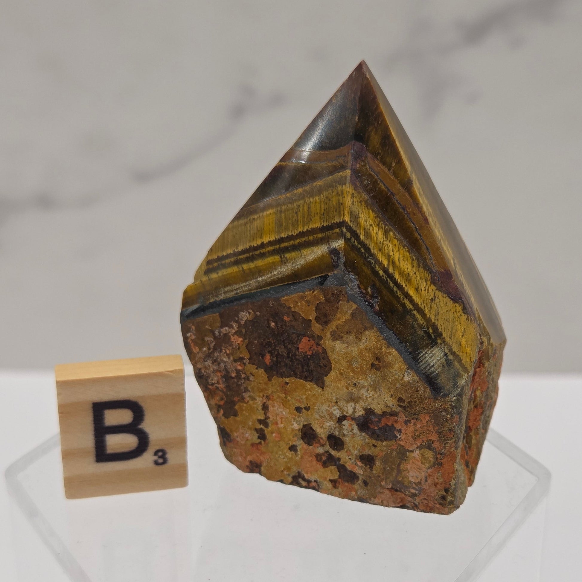 Tigers Eye specimen on a white background with a small wooden block displaying 'B' 