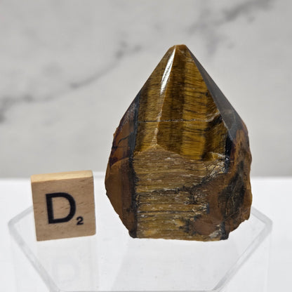 Tigers Eye specimen on a white background with a small wooden block displaying 'D' 
