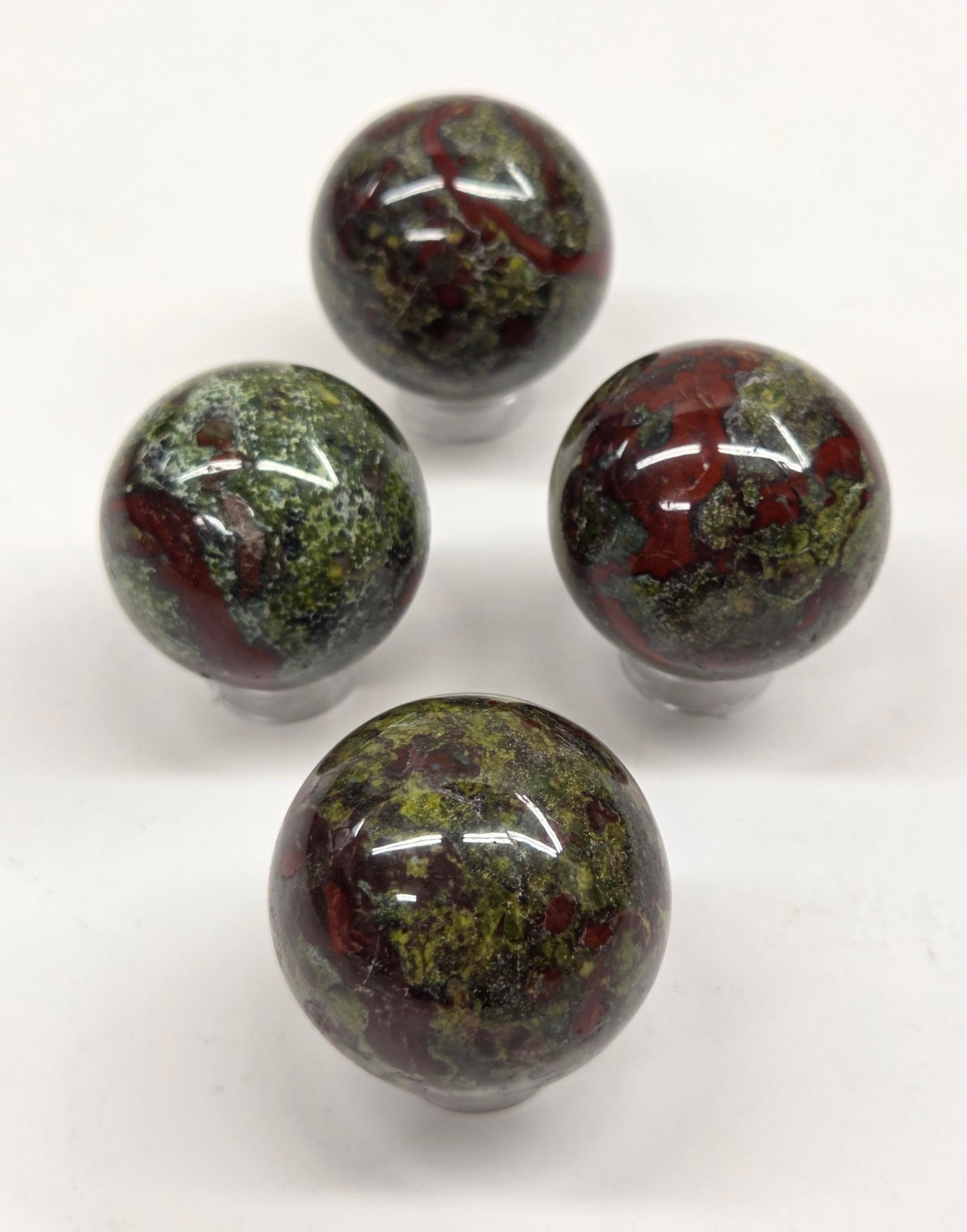 Four dragons blood spheres with red and green coloring on a white background