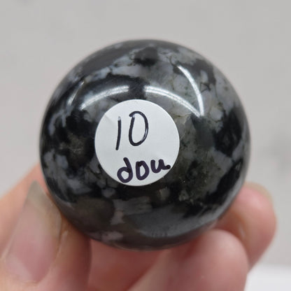 Person holding a dark marbled crystal sphere against a neutral background