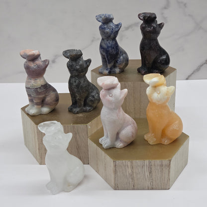 Set of small cat carvings, each with a butterfly on their nose, on a wooden stand against a marble background