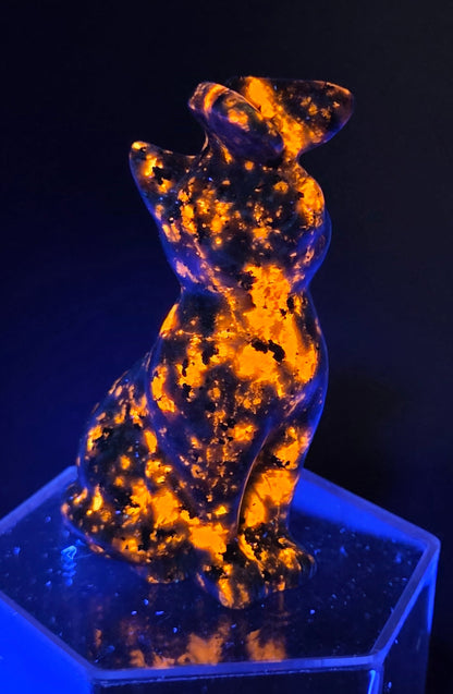 Yooperlite crystal cat-shaped carving with a butterfly on the nose, under UV light
