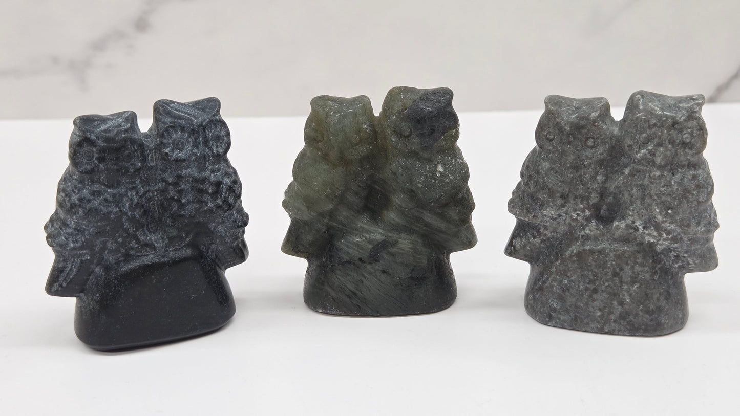 Three crystal carvings of owls on a white surface with a light gray background