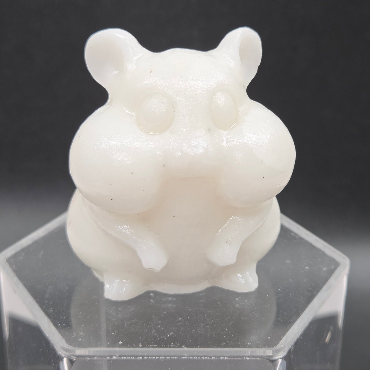 White Jade carving of a chipmunk on an acrylic block against a dark background
