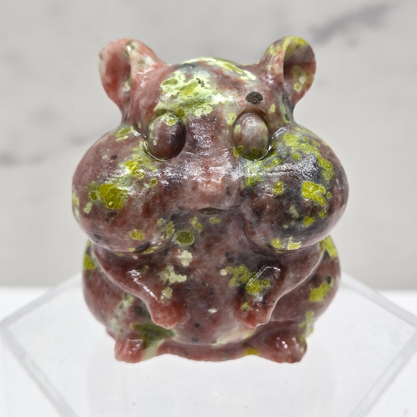 Red Serpentine carving of a chipmunk on an acrylic block against a white background