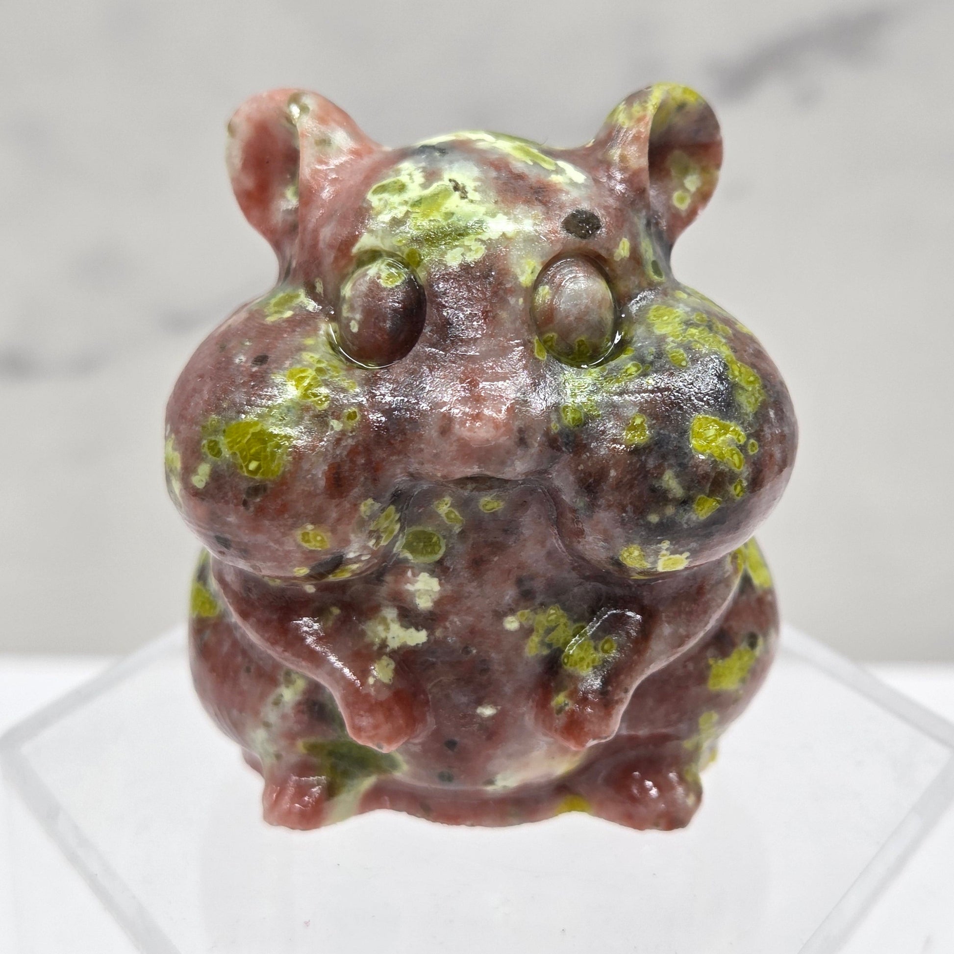 Red Serpentine carving of a chipmunk on an acrylic block against a white background