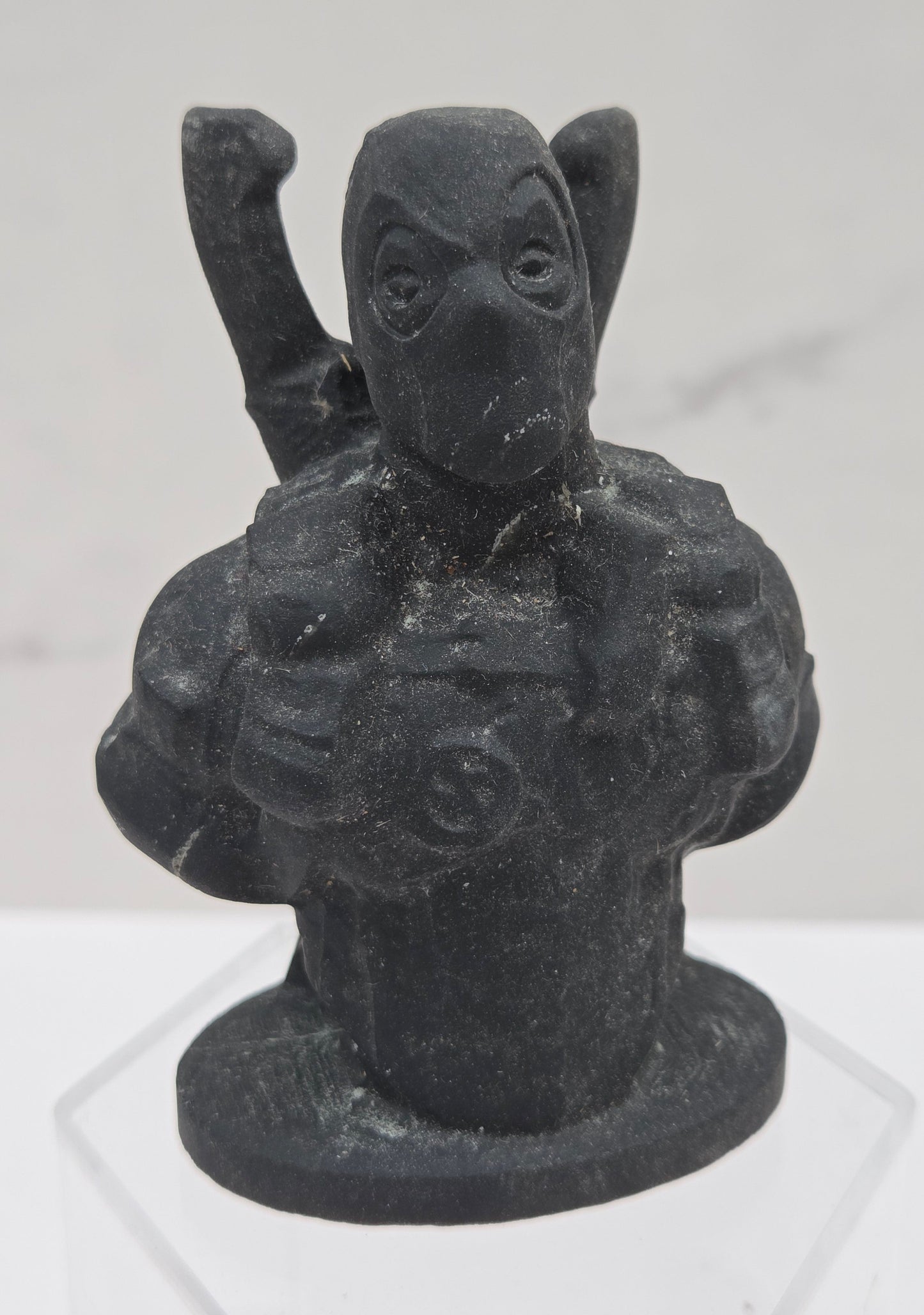 Black stone sculpture of Deadpool on a white background