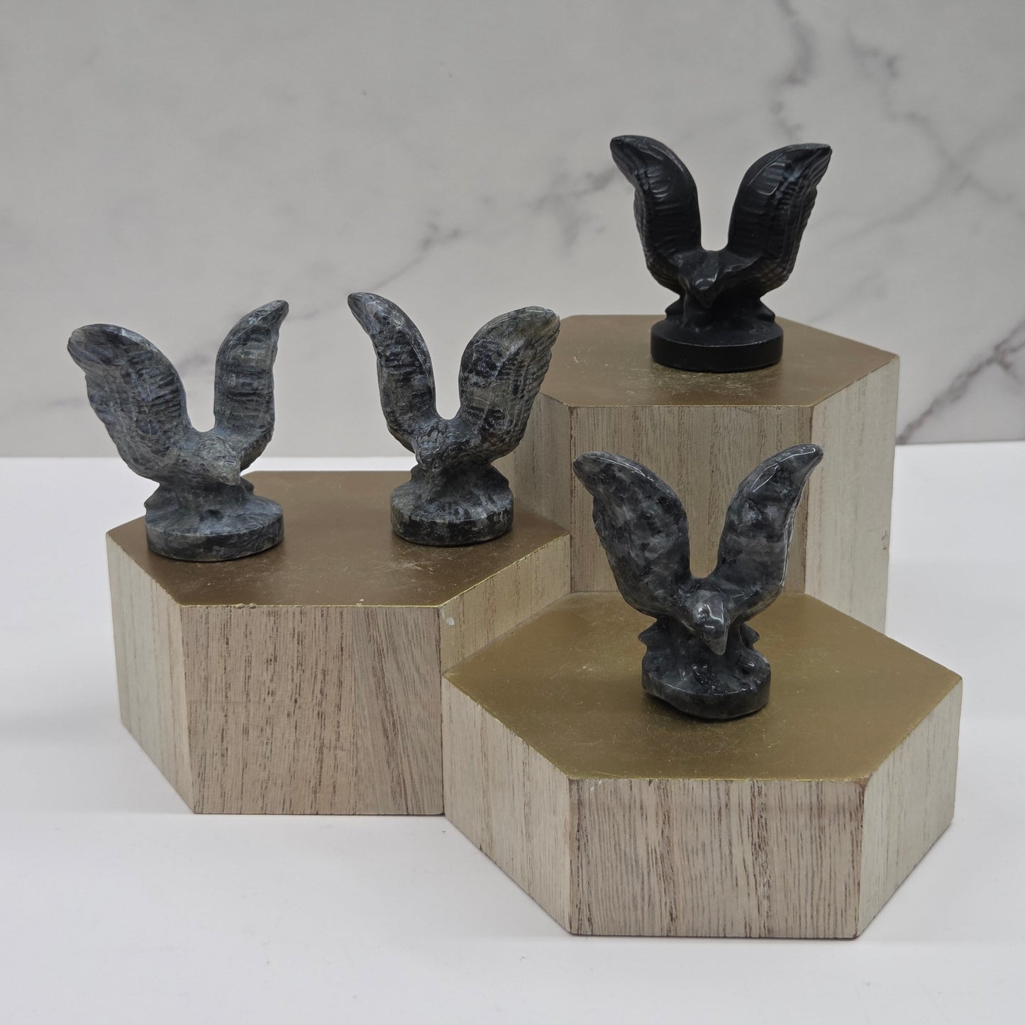 Decorative bird sculptures on wooden stands against a marble background