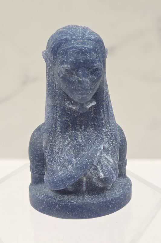 Blue stone sculpture of a figure on a light gray background