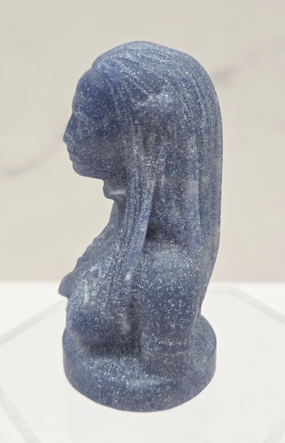 Blue stone sculpture of a figure on a light gray background