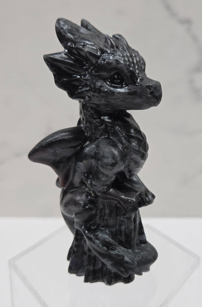 Dragon carving made of garnet sitting on an acrylic stand against a neutral background