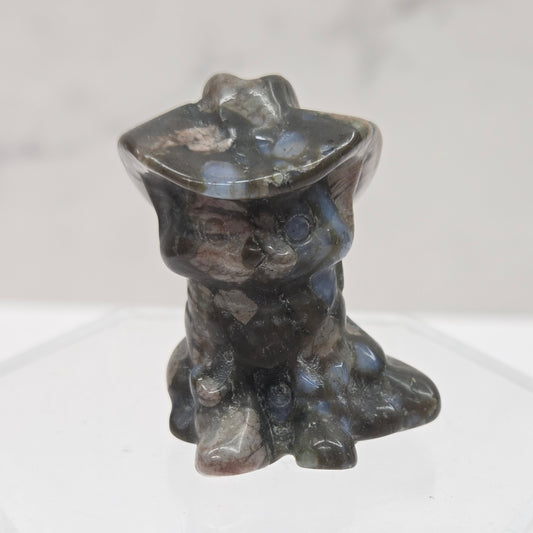 Black, blue and pink stone carving of a cat with a cowboy hat on an acrylic stand against a white background