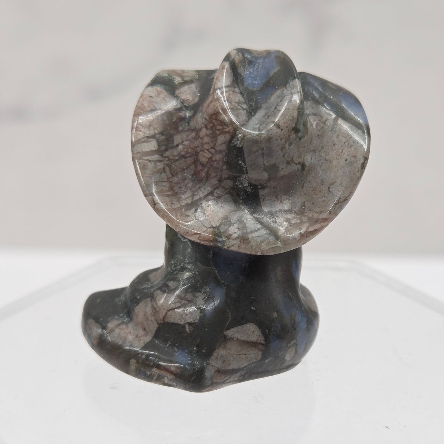 Black, blue and pink stone carving of a cat with a cowboy hat on an acrylic stand against a white background