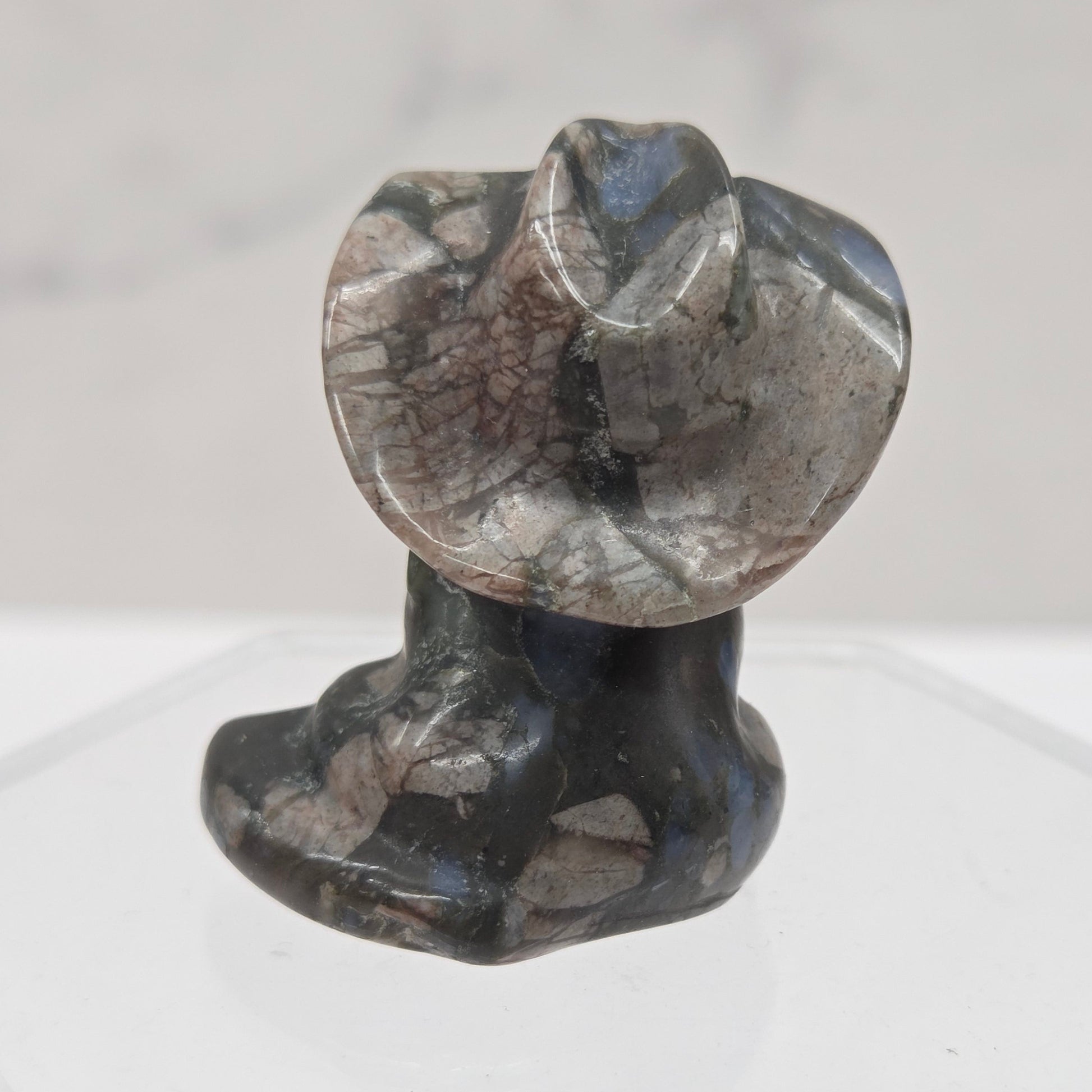 Black, blue and pink stone carving of a cat with a cowboy hat on an acrylic stand against a white background