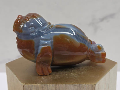 Brown and grey crystal sculpture of a walrus on a hexagonal base with a marble background