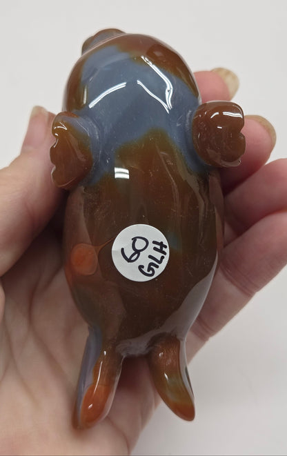 Hand holding a small glass figurine with a label on a white background