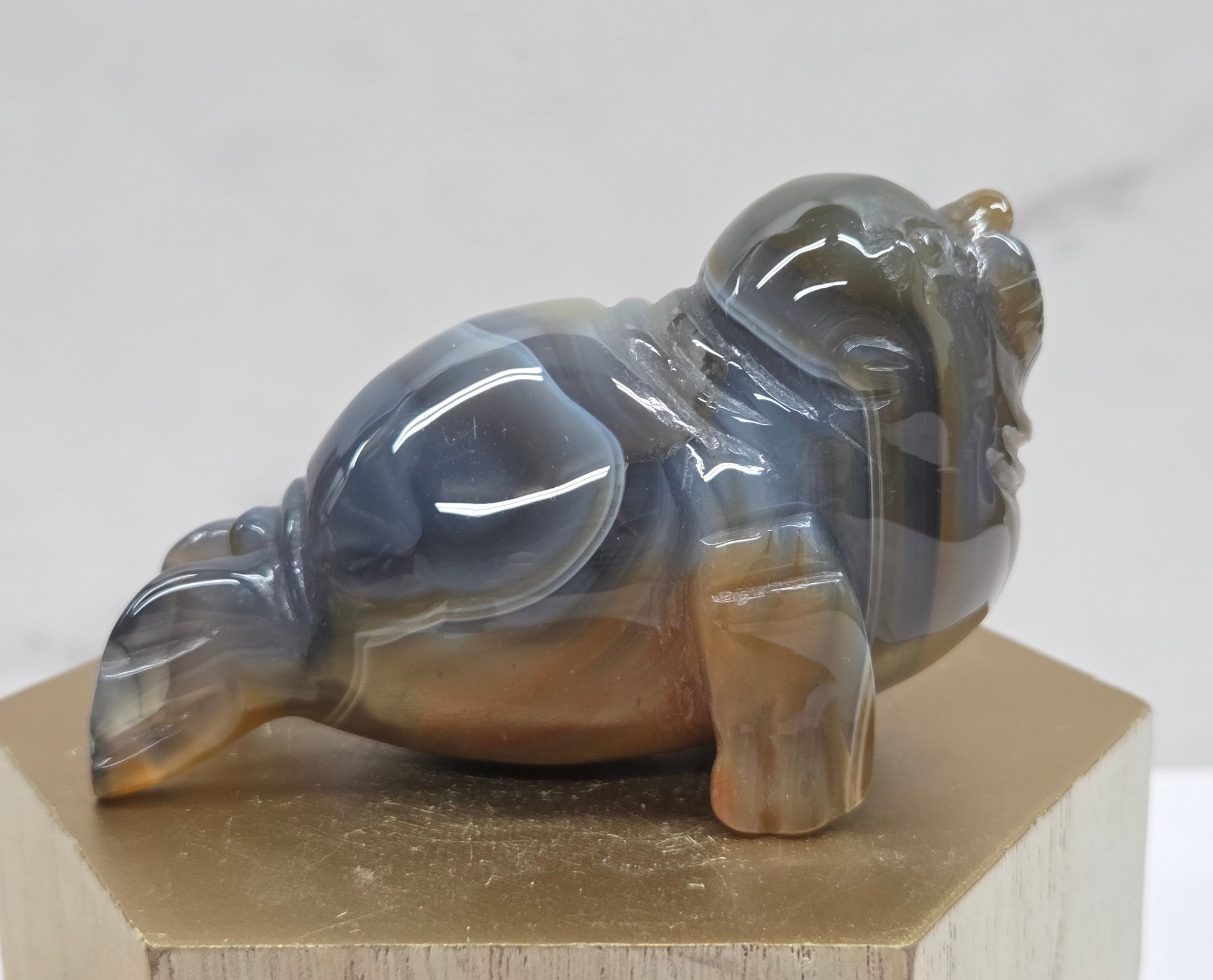 Brown and grey crystal sculpture of a walrus on a hexagonal base with a marble background
