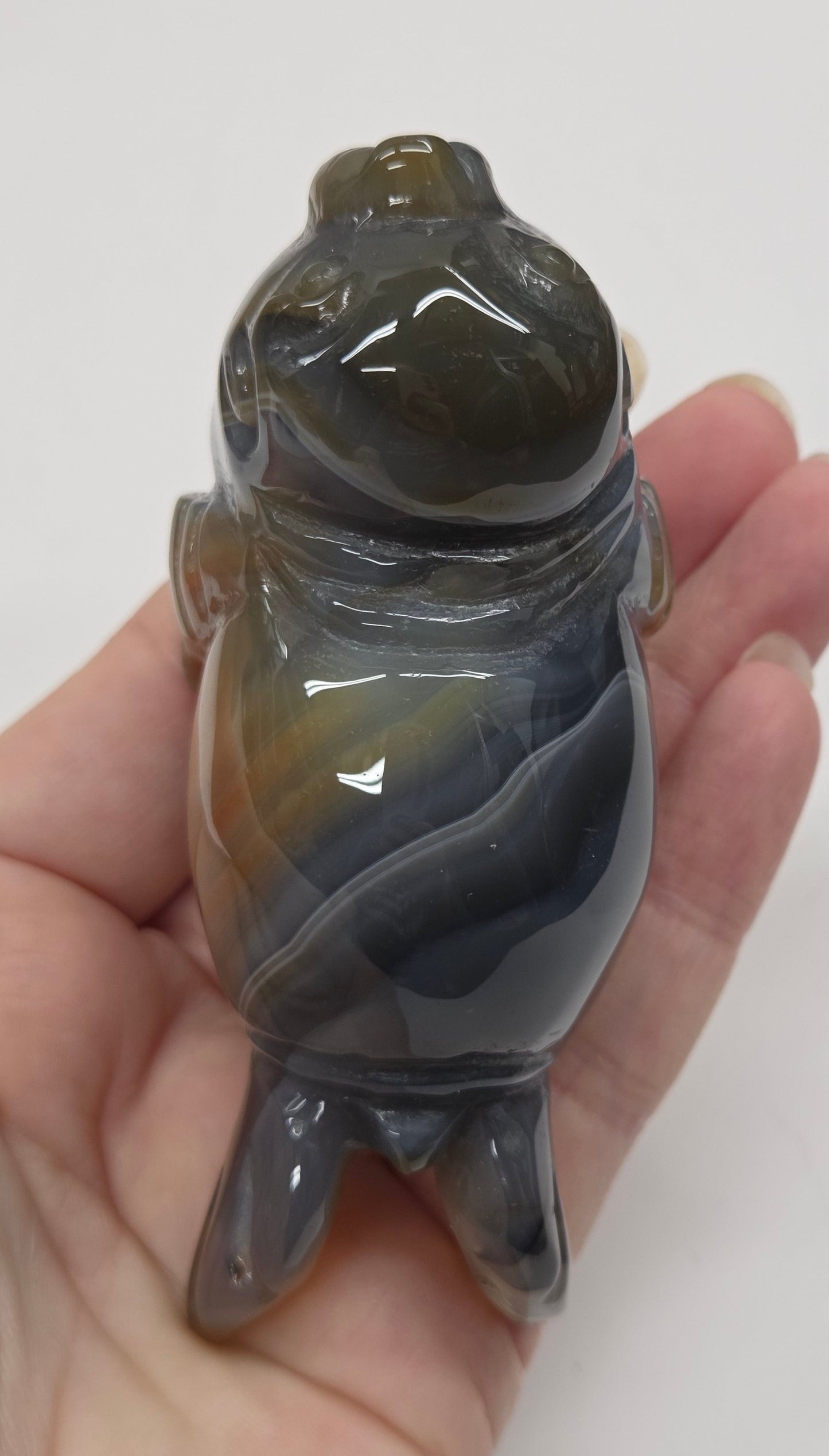 Hand holding a gray crystal walrus sculpture against a white background