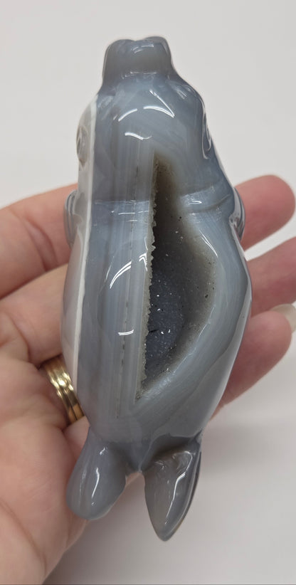 Grey crystal sculpture of a walrus on a hexagonal base with a marble background