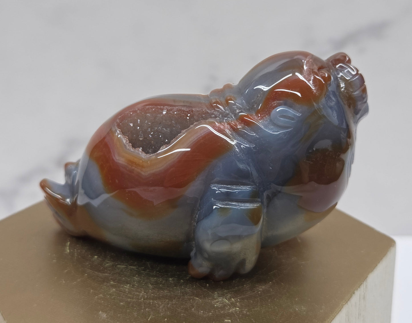 Brown and grey crystal sculpture of a walrus on a hexagonal base with a marble background