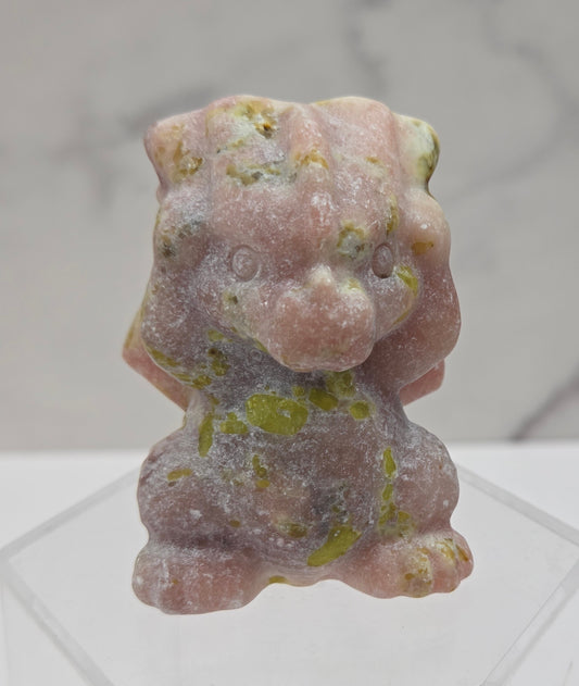 Pink and yellow dragon carving on an acrylic stand against a neutral background