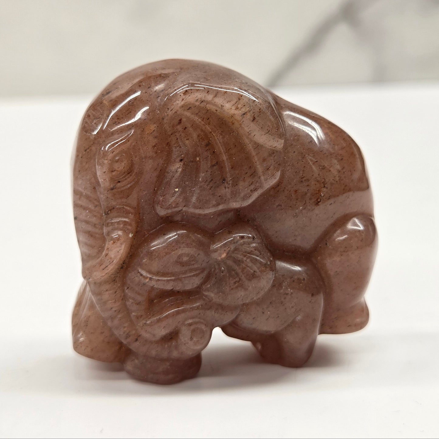 Strawberry Quartz elephant with baby carving on a neutral background