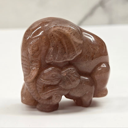 Strawberry Quartz elephant with baby carving on a neutral background