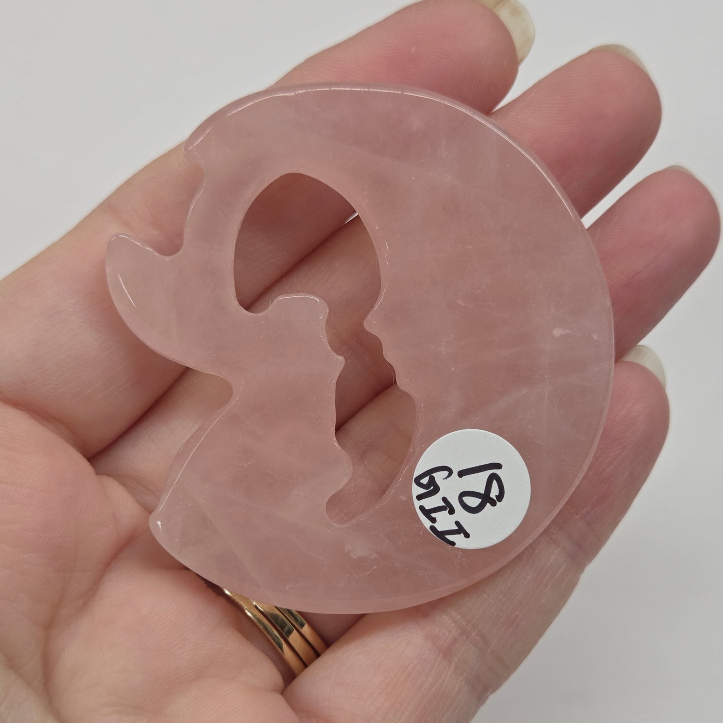 Pink rose quartz fairy on a moon against a neutral background