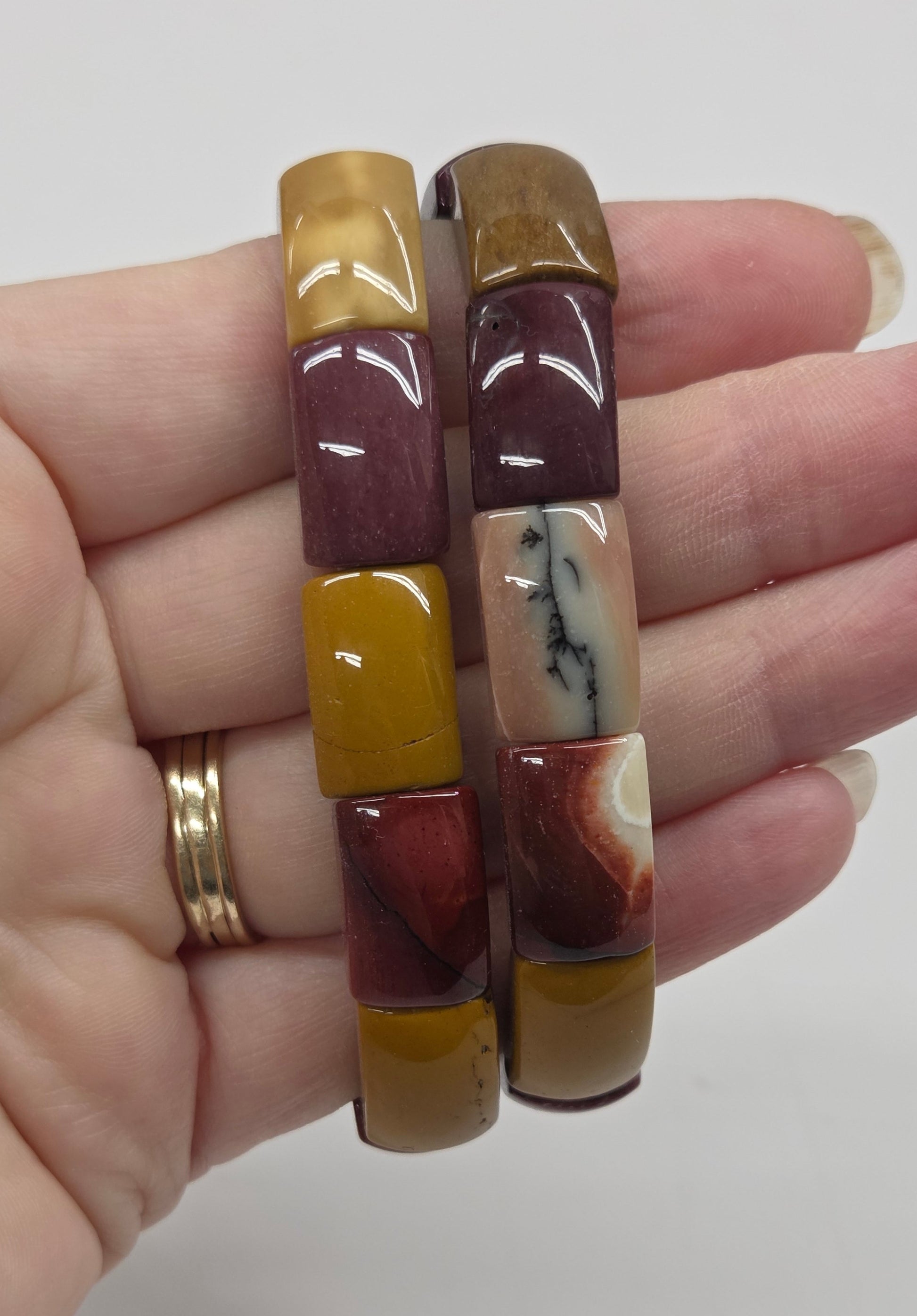 Hand wearing two marbled patterned bracelets on a plain background