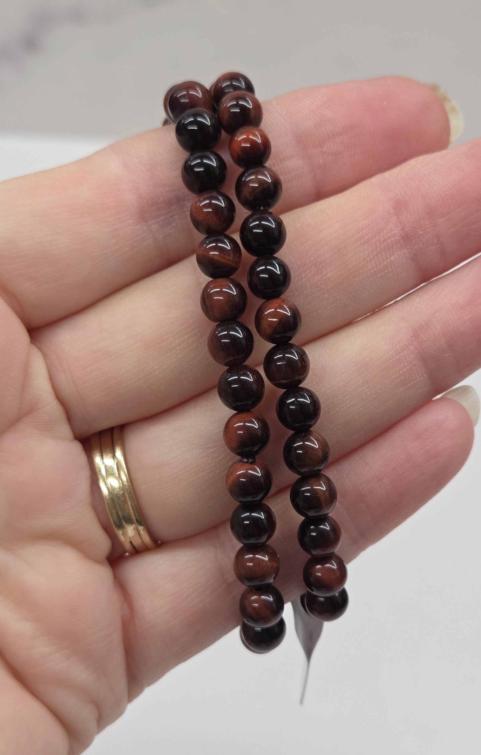 Hand holding two beaded bracelets with a neutral background
