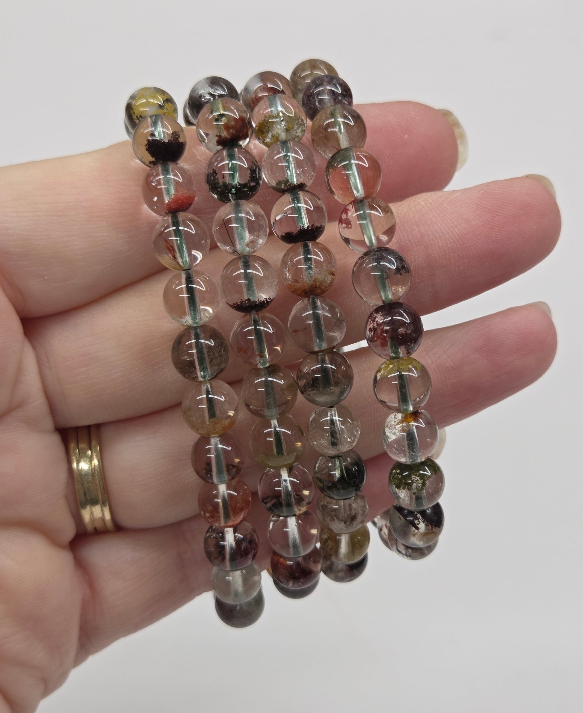 Hand holding a beaded bracelet against a plain background