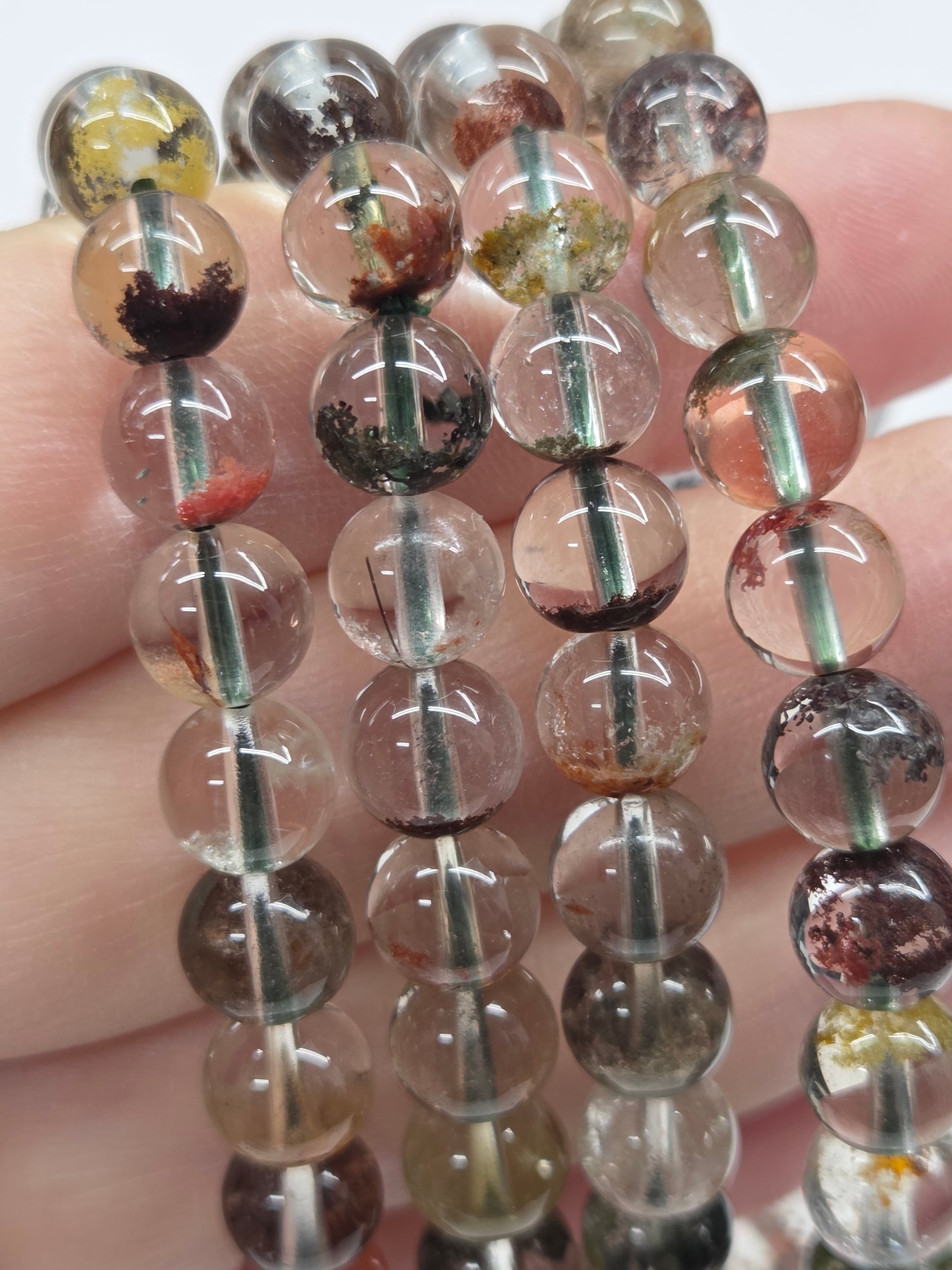 Close-up of a string of transparent beads with embedded stones held between fingers.