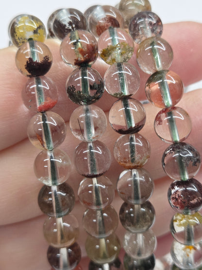 Close-up of a string of transparent beads with embedded stones held between fingers.