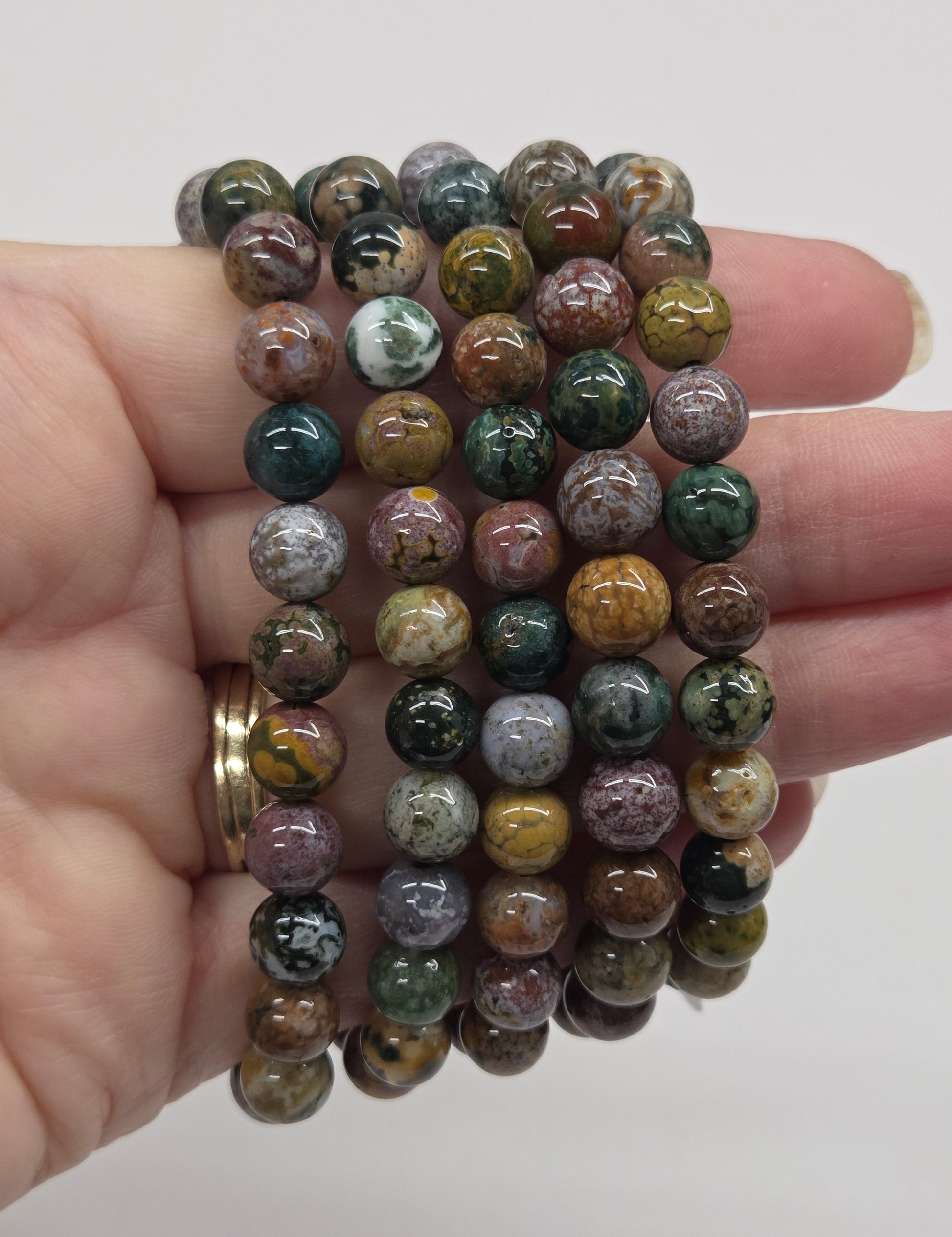Stack of multicolored beaded bracelets held in a hand against a plain background