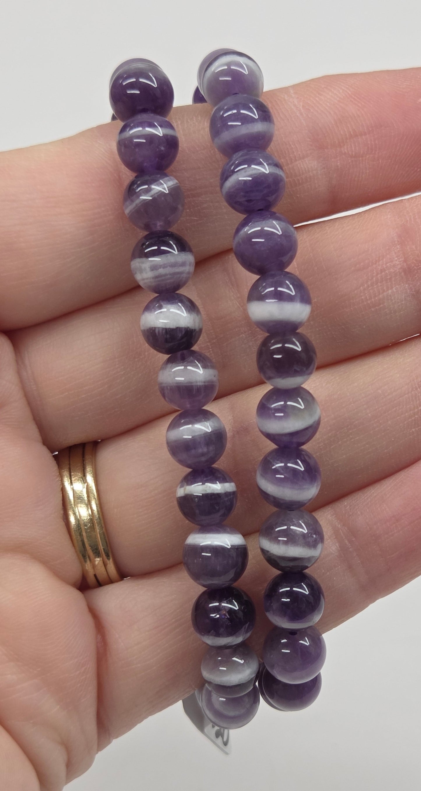 Purple beaded bracelet on a hand with a plain background