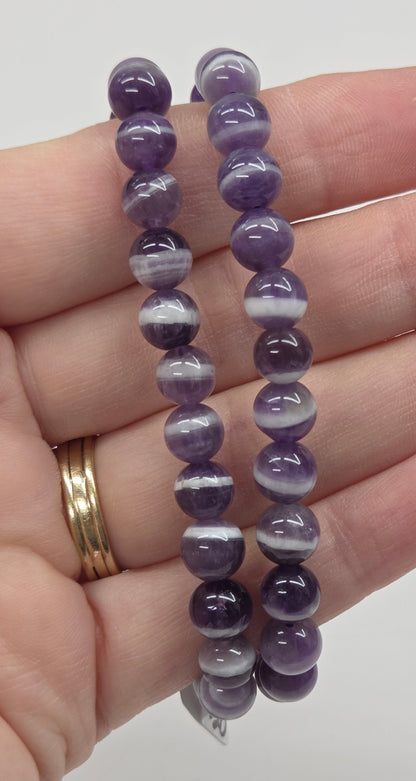 Purple beaded bracelet on a hand with a plain background