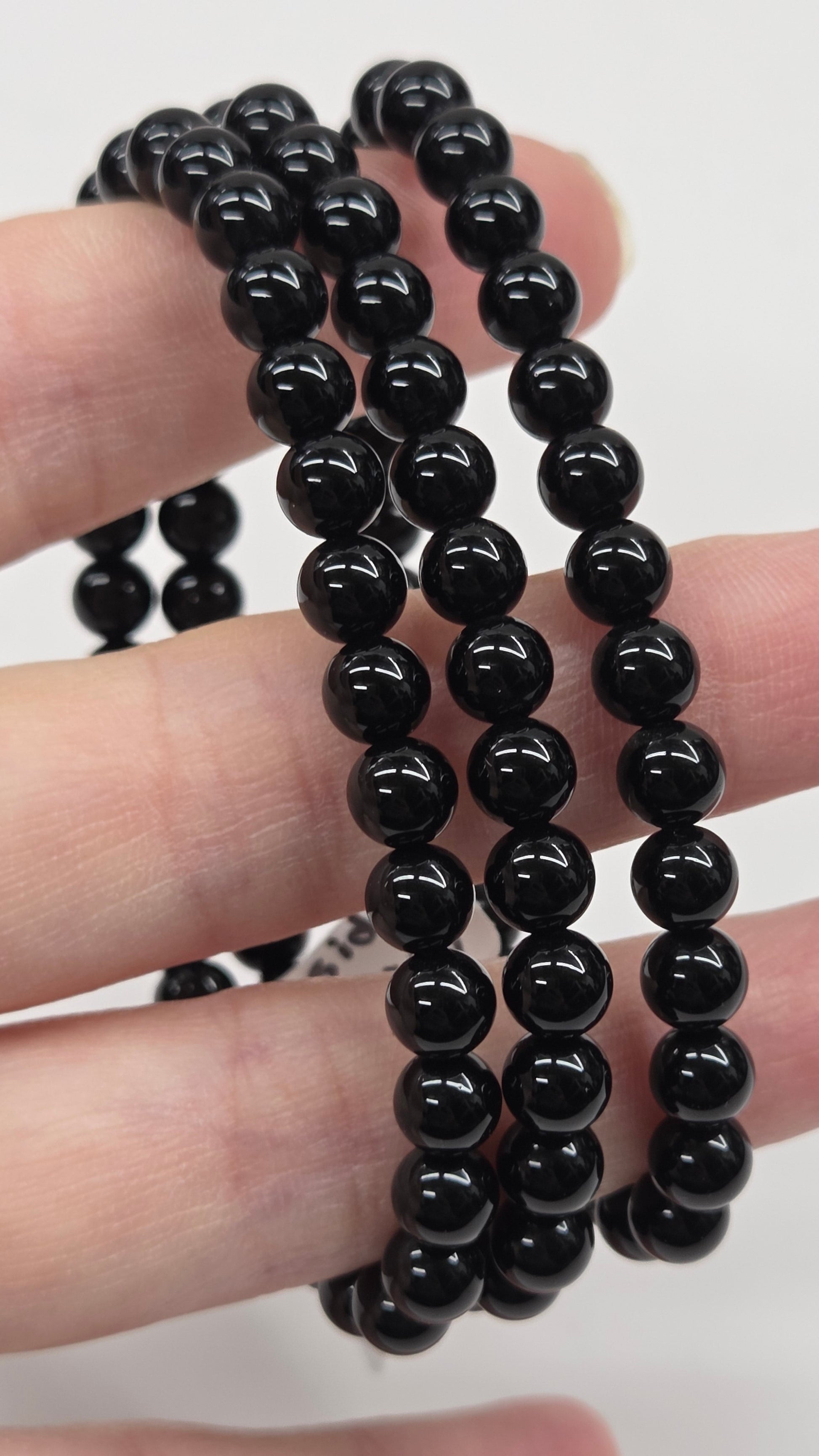 Black beaded bracelet on a hand with a plain background