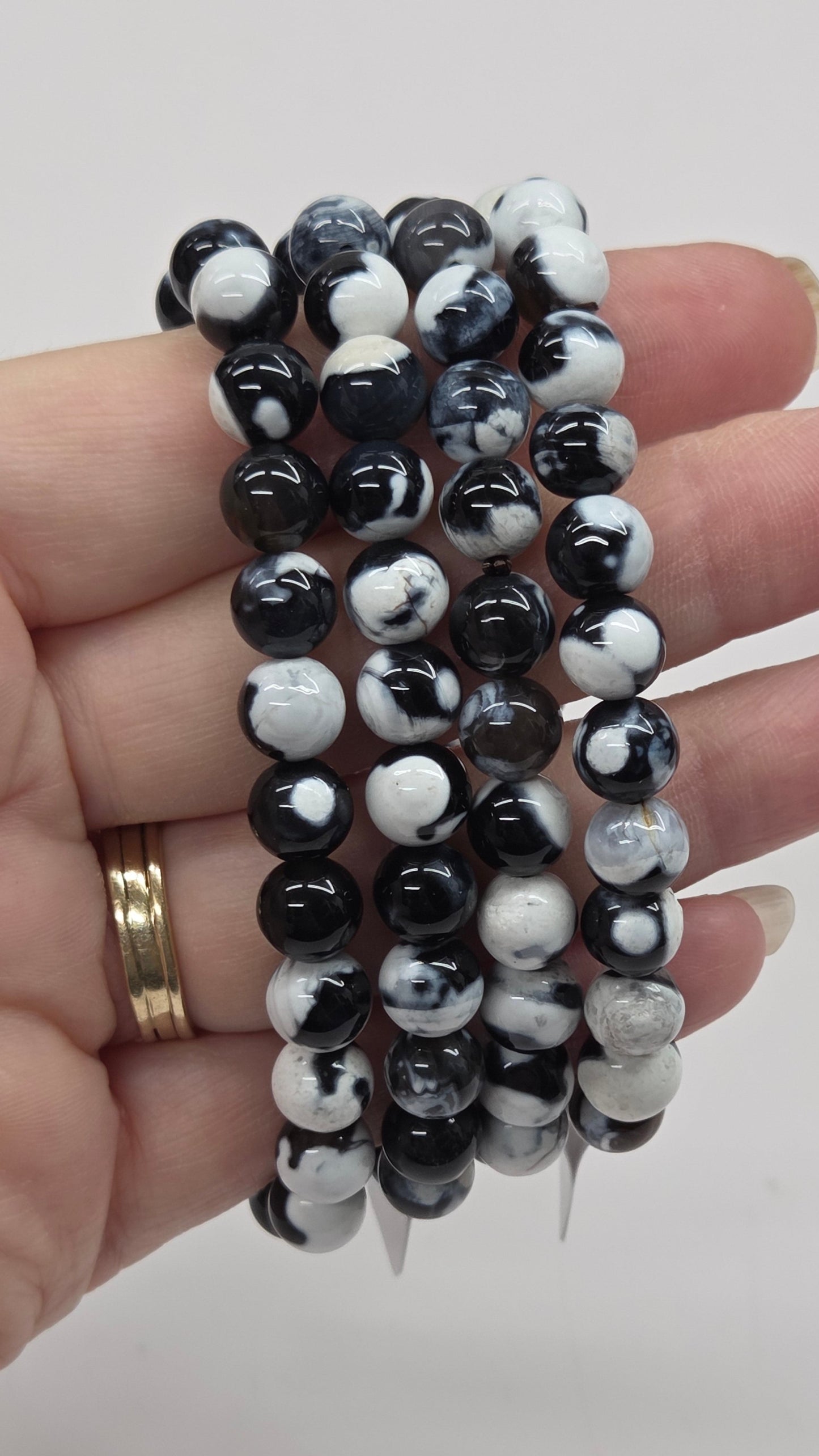 Hand holding black and white beaded bracelets against a plain background