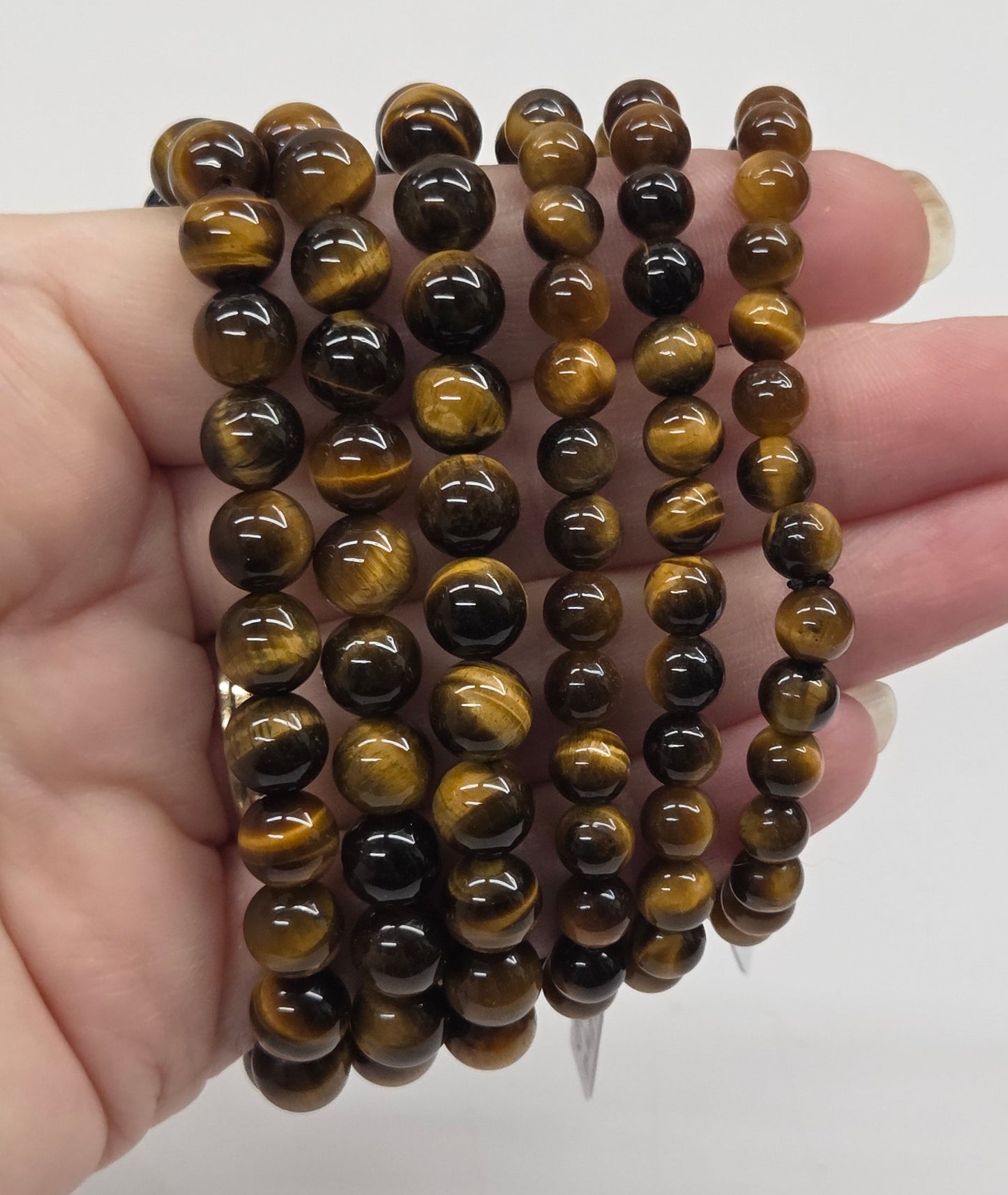 Stack of brown beaded bracelets held in a hand against a white background