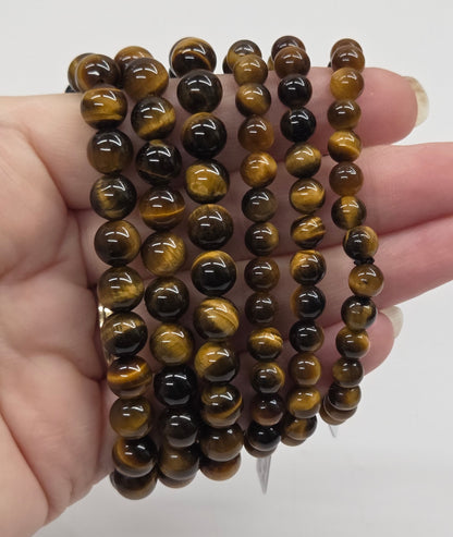 Stack of brown beaded bracelets held in a hand against a white background