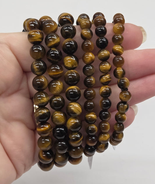 Stack of brown beaded bracelets held in a hand against a white background