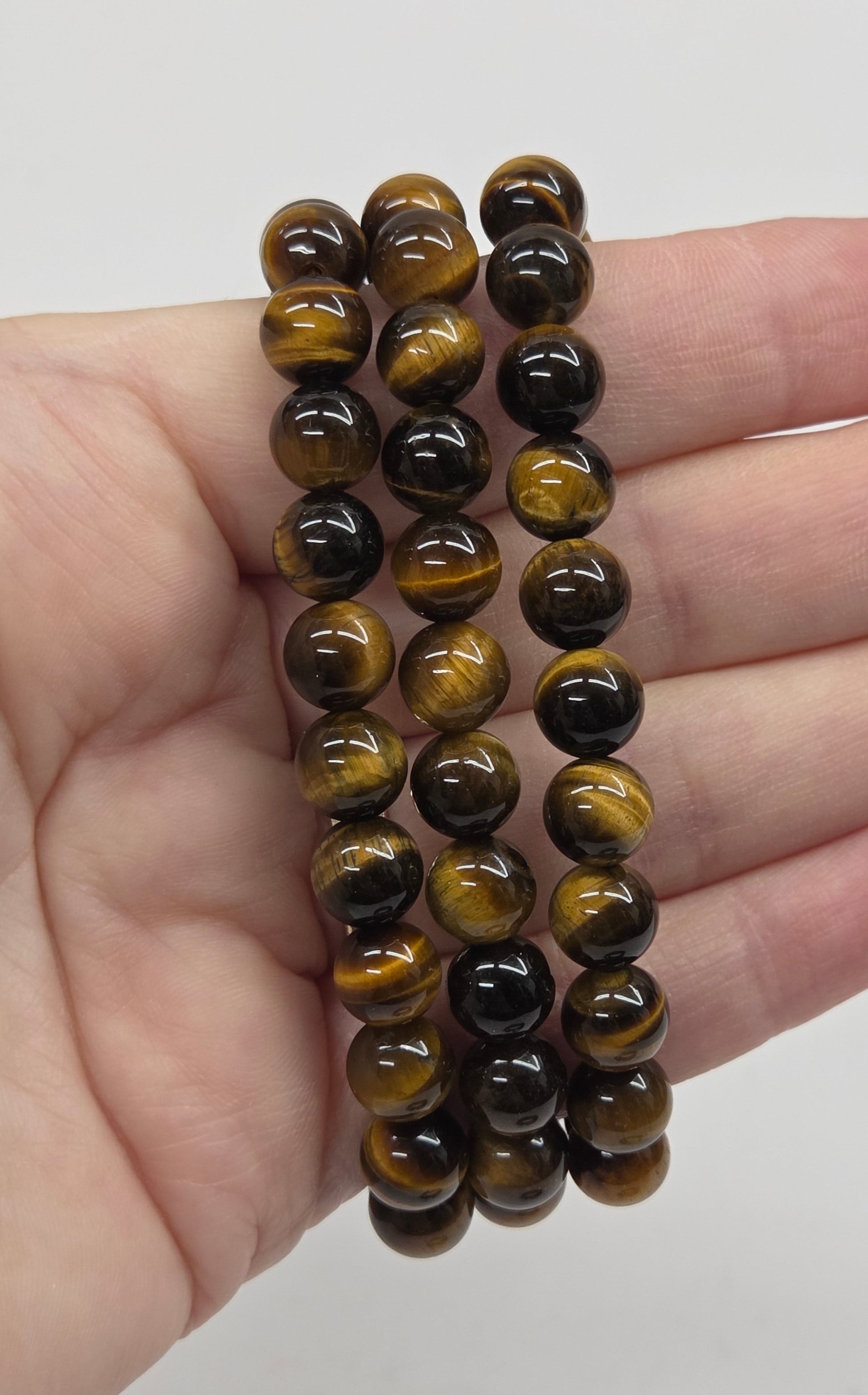 Three beaded bracelets on a hand against a plain background
