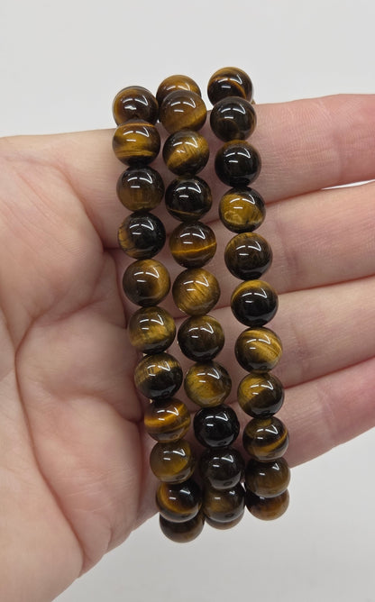 Three beaded bracelets on a hand against a plain background