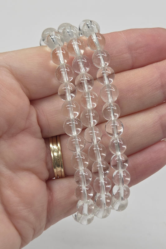 Clear beaded bracelets on a hand with a plain background