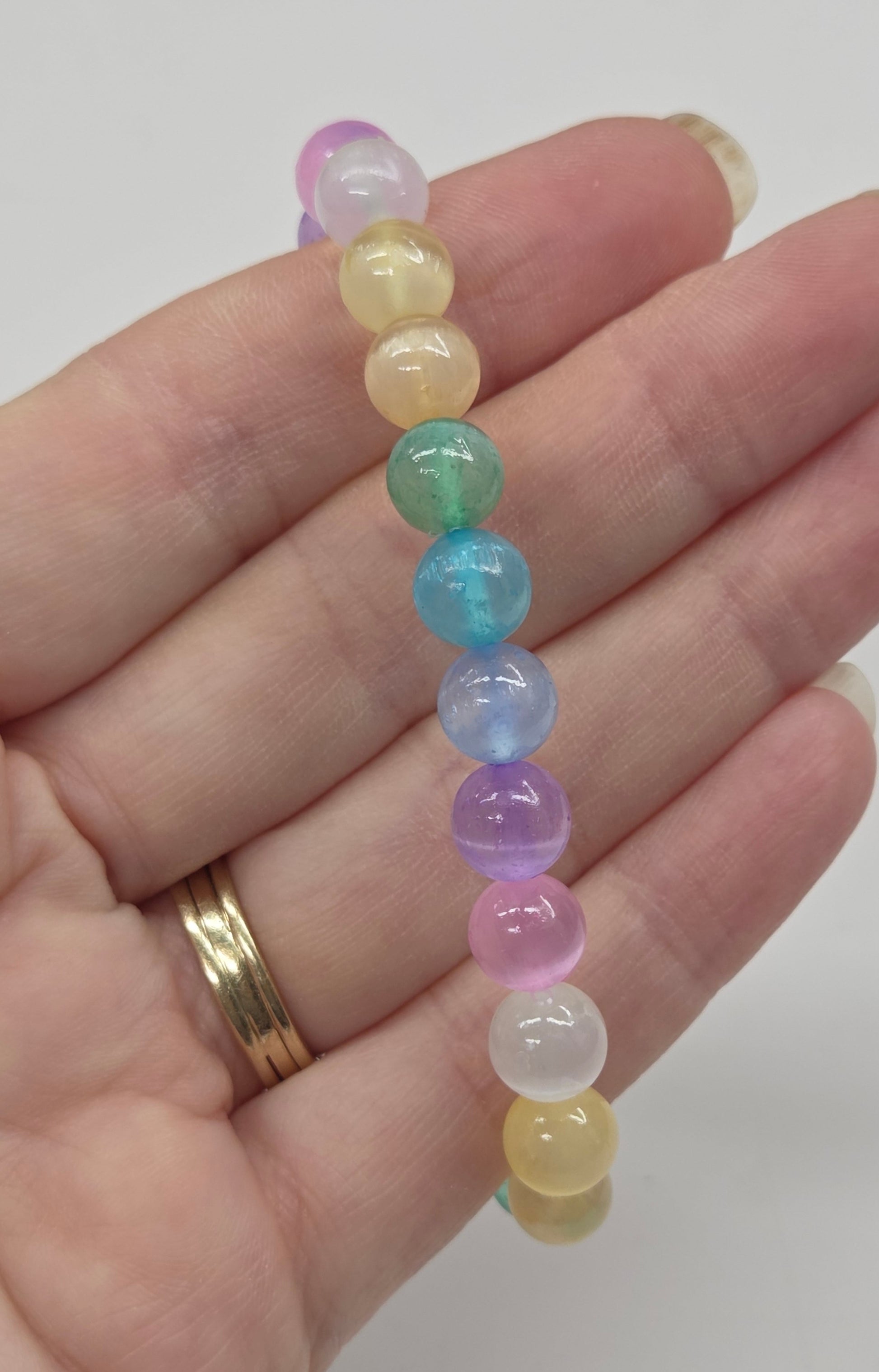 Colorful beaded bracelet on a hand with a plain background