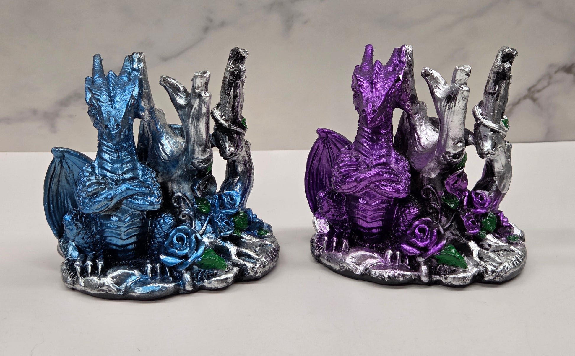 Plastic dragon shaped sphere holders in blue and purple against a white background